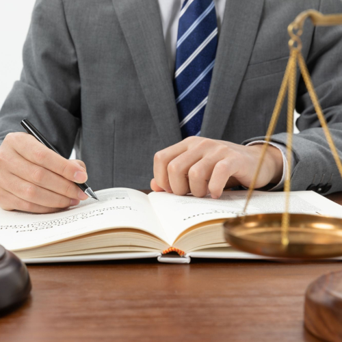 closeup-shot-person-writing-book-with-gavel-table-1